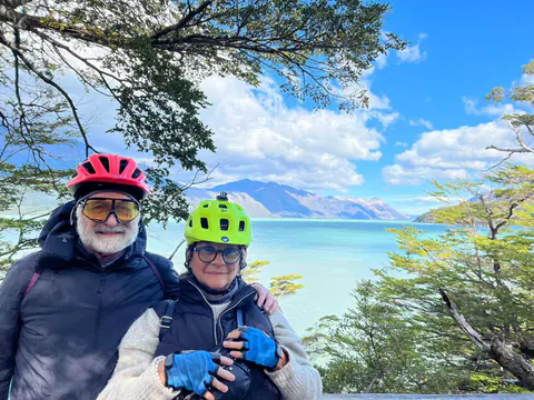 Una pareja con cascos sonríe frente al lago
