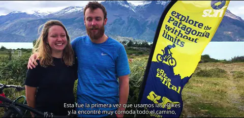 Una pareja de viajeros junto a la bandera de SURí, frente al lago O'Higgins
